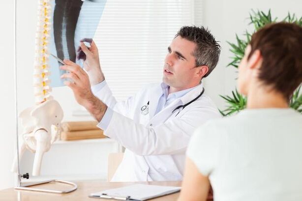 Il medico mostra il danno alla colonna vertebrale causato dall'osteocondrosi cervicale